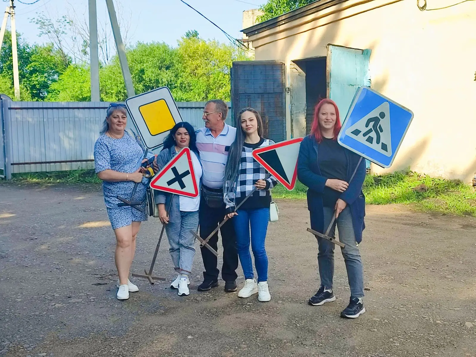 Группа людей с дорожными знаками во дворе у гаражей